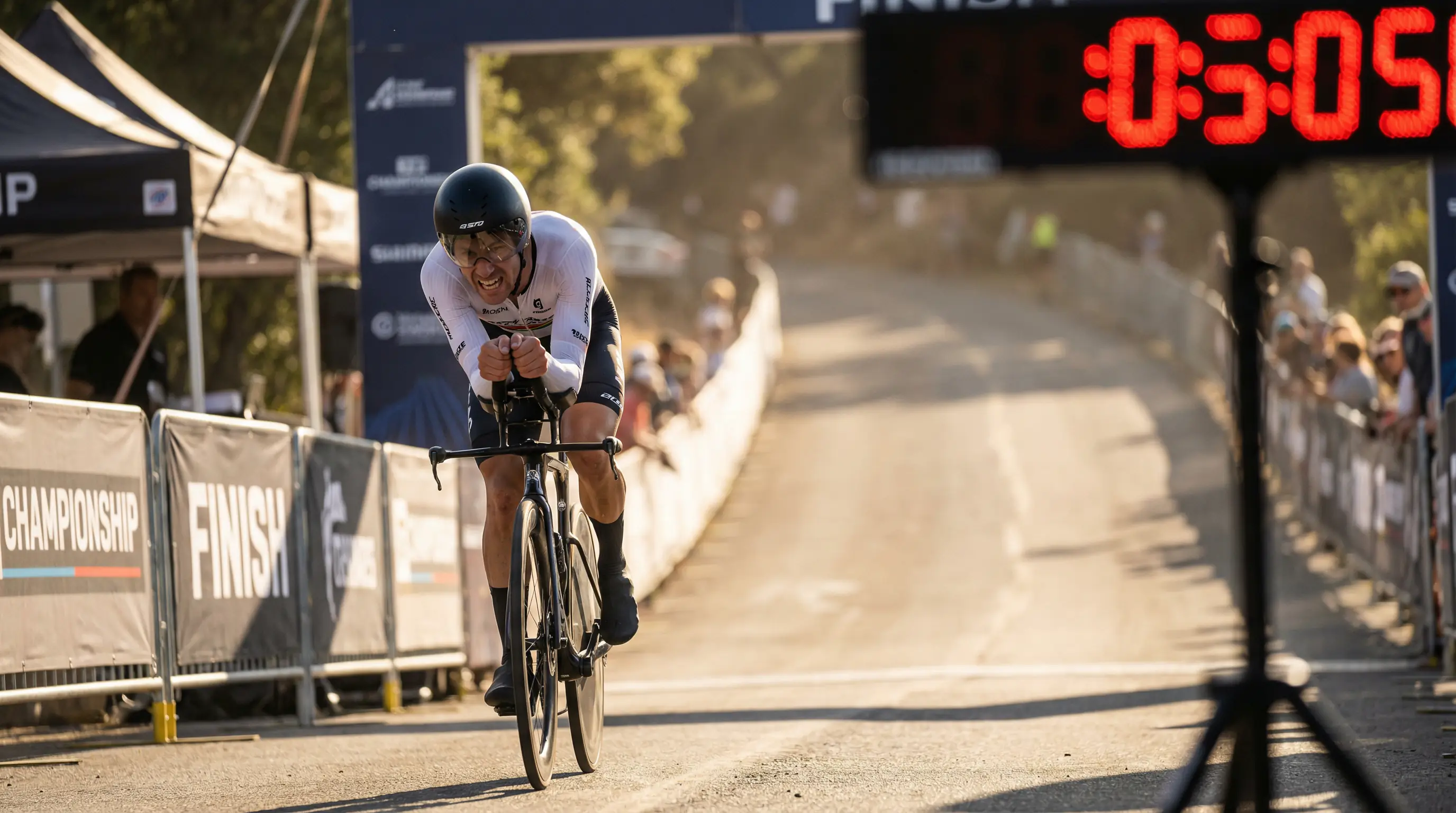 Ciclista cruzando la meta de una contrarreloj con el reloj digital mostrando el tiempo al fondo