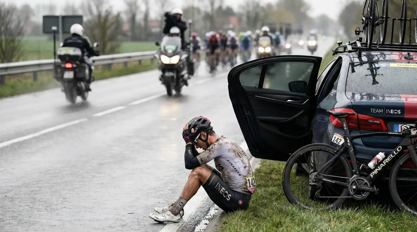 Ciclista abandonando una carrera tras una caída con el coche del equipo detrás en la carretera